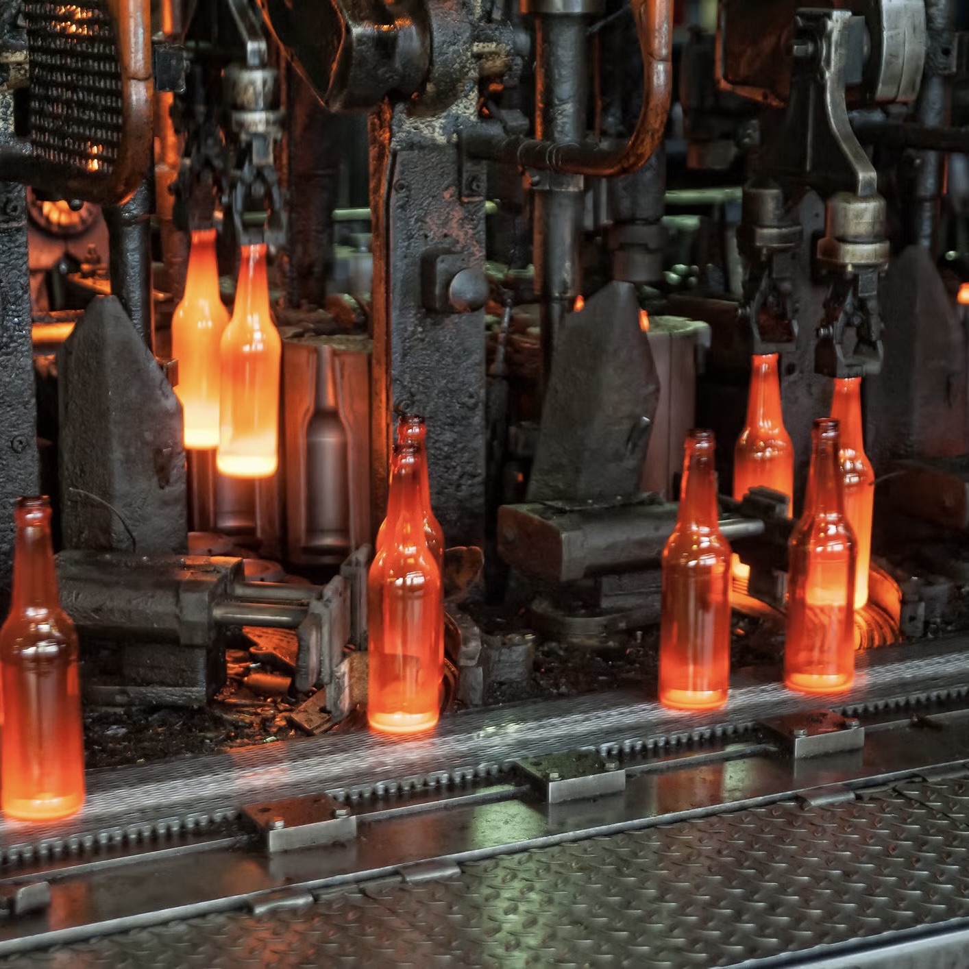 Glowing glass bottles emerging from a production line