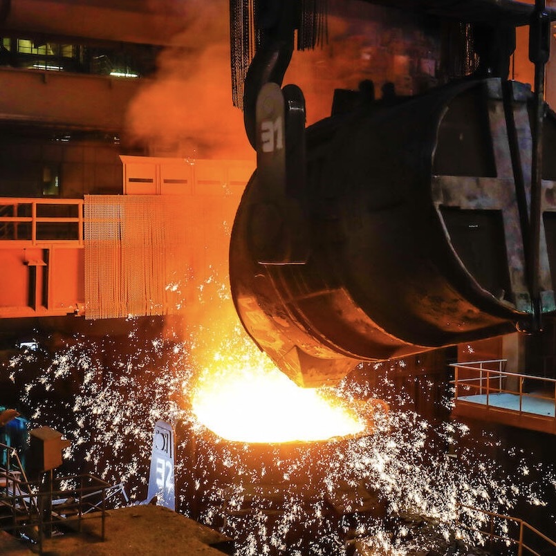Molten metal being poured in a steel mill, sparks and intense heat