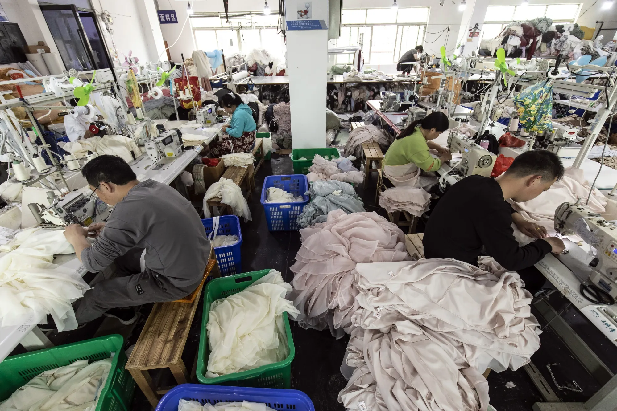 Operators working on sewing and finishing lines in a garment workshop, illustrating upstream Scope 3 Category 1 emissions in apparel.