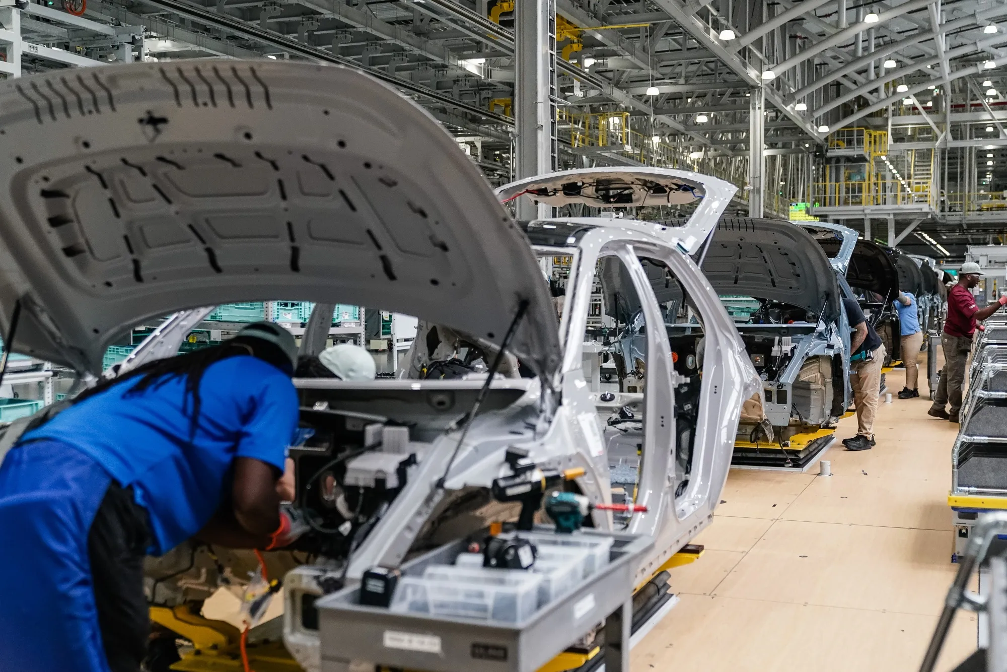 Vehicle bodies moving along an automotive assembly line, illustrating where automotive Scope 3 emissions shift as electrification advances.
