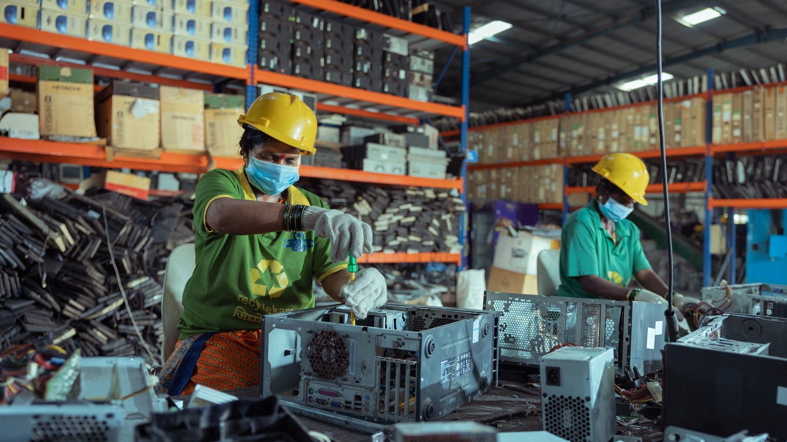 Workers sorting discarded electronic and consumer products in a recycling facility, illustrating Scope 3 Category 12 end-of-life treatment.