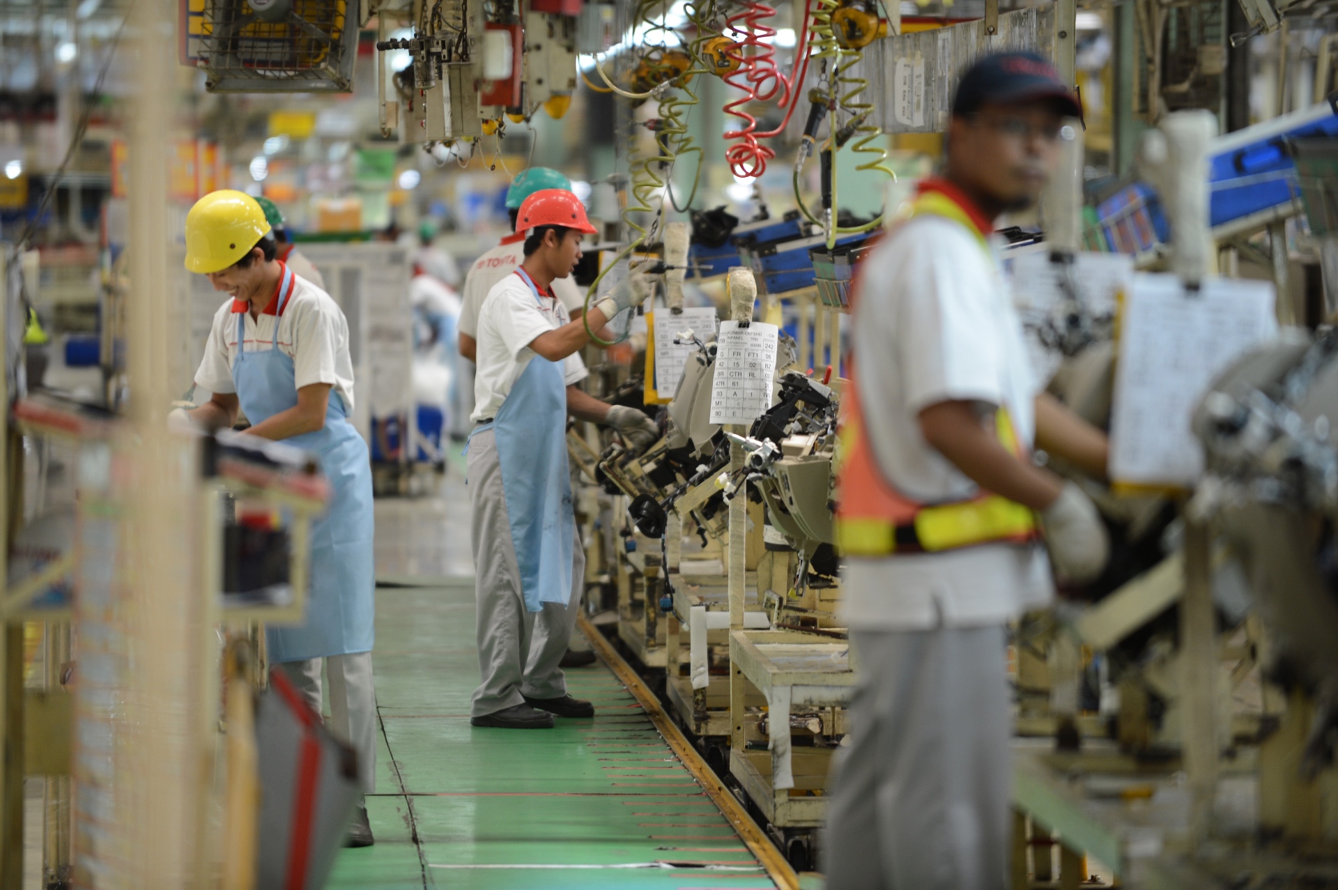 Automotive supplier assembly line with workers and components moving down a conveyor — upstream Scope 3.4 transport and distribution
